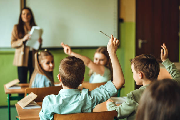 istock Elementary school children in classroom putting up hands for asking questions 1456222099