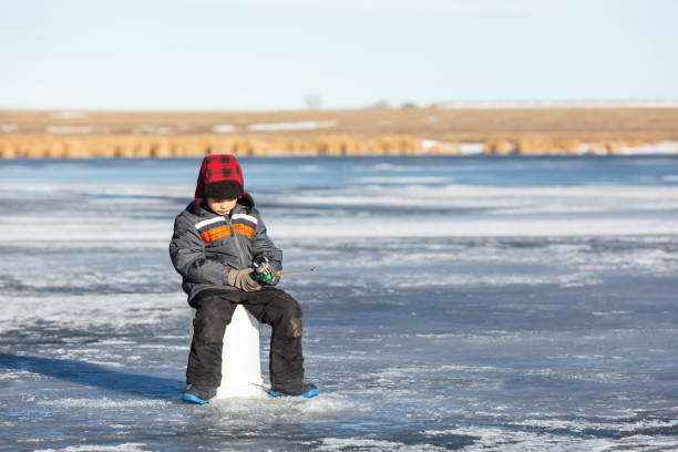 istock Young Boy Sitting on Bucket While Ice Fishing 1456222136
