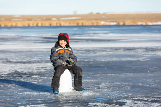 istock Young Boy Sitting on Bucket While Ice Fishing 1456222149