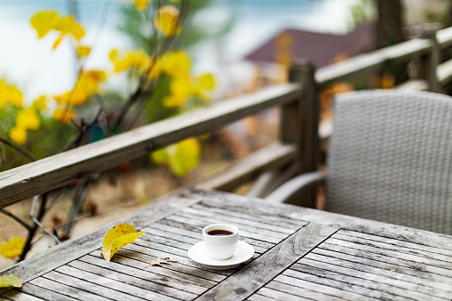 Cup with black coffee on the wooden table outdoors