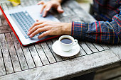 Unrecognisable man working remote with cup of coffee