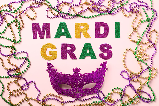 Mardi Gras party concept. Flat lay lettering Mardi Gras, colorful beads and carnival mask.