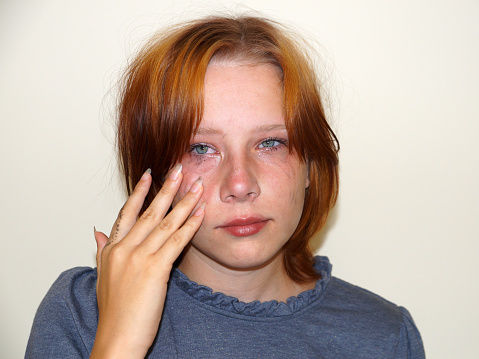 portrait of a sad red-haired teenage girl with a tear-stained face.