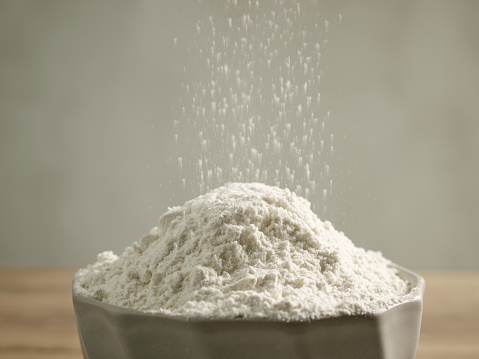 flour pouring into bowl, selective focus
