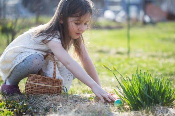 istock spring fun - finding eggs for easter outdoor in countryside. child looks and takes egg on sunny day. hunt in backyard. 1456226866