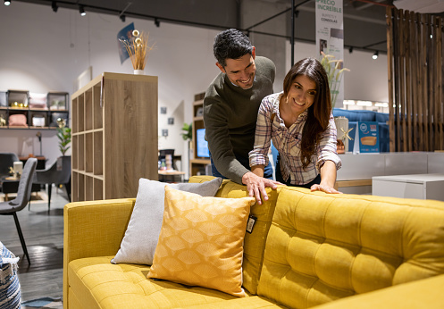 Happy Latin American couple in a furniture store looking at sofas to buy - lifestyle concepts