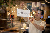 Retail clerk hanging an open sign at the door of a furniture store