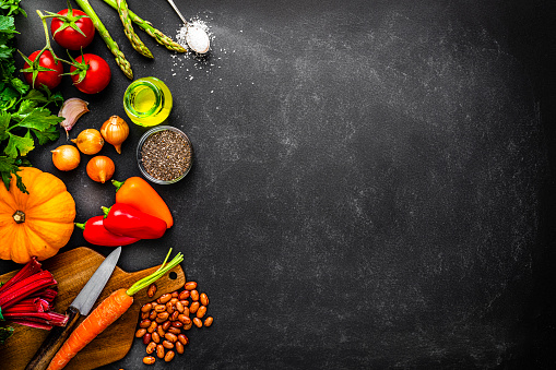 Overhead view of healthy colorful vegetables arranged at the left of a dark background leaving useful copy space for text or logo. High resolution 42Mp studio digital capture taken with SONY A7rII and Zeiss Batis 40mm F2.0 CF lens