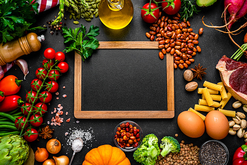 Overhead view of healthy colorful vegetables arranged all around a slate chalkboard and leaving useful copy space for text or logo at the center. High resolution 42Mp studio digital capture taken with SONY A7rII and Zeiss Batis 40mm F2.0 CF lens