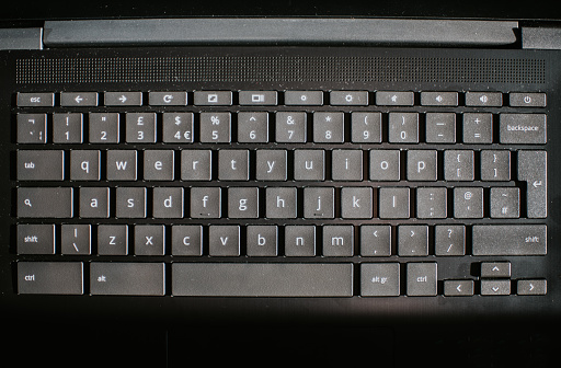 Close-up image of a black laptop computer keyboard on a white surface.