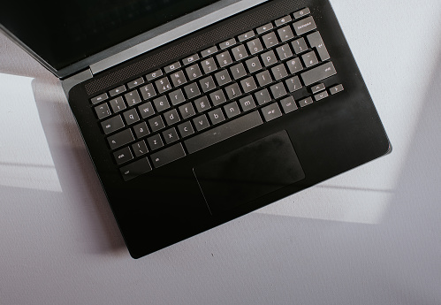 Close-up image of a black laptop computer keyboard on a white surface.