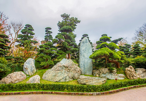 Superb View of the cliffs in Nan Lian Park with idyllic topiary podocarpus and pine trees. Entrance to the garden n tropical Hong Kong. Interesting lawns and topiary plants and curly rocks. Free of charge.