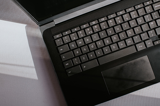 Close-up image of a black laptop computer keyboard on a white surface.