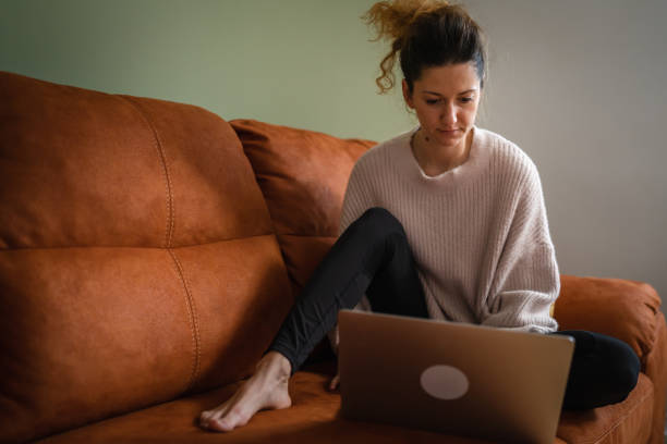 istock One woman sit on sofa bed at home work on the laptop computer 1456235411