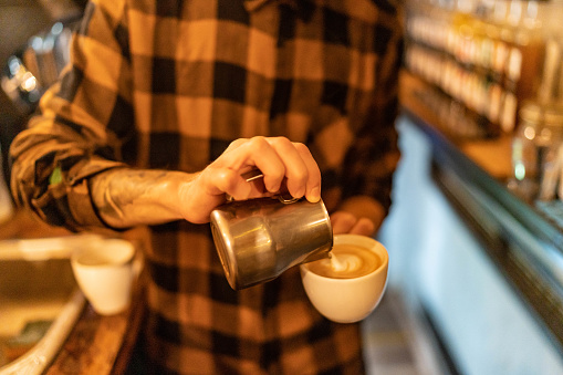 Male barista's hand making latte cappuccino art