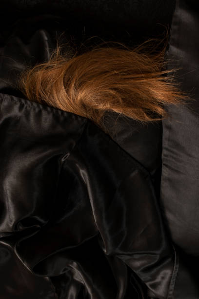 istock Female red hair on black bed sheet. 1456238266