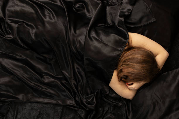 istock Woman sleeps in a bed on black bed sheet. 1456238277