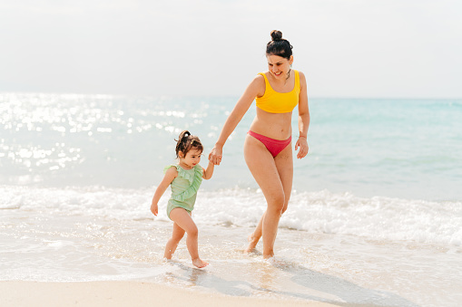 Photo of a young mother with her baby girl, enjoy evening walks and fresh air at the  beach
