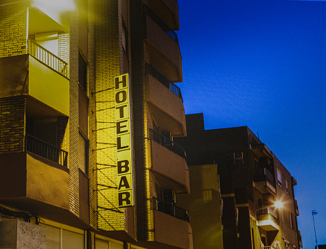 Hotel bar sign on the facade of a humble building at night