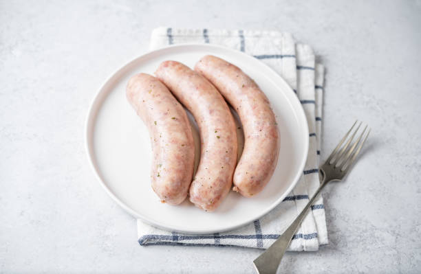 istock Raw uncooked sausages in cream sauce in a plate 1456244384