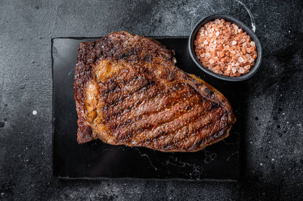 焼き和牛リブアイステーキ、霜降り牛の塩漬け。黒い背景。平面図 - rib eye steak beef cutting board meat ストックフォトと画像