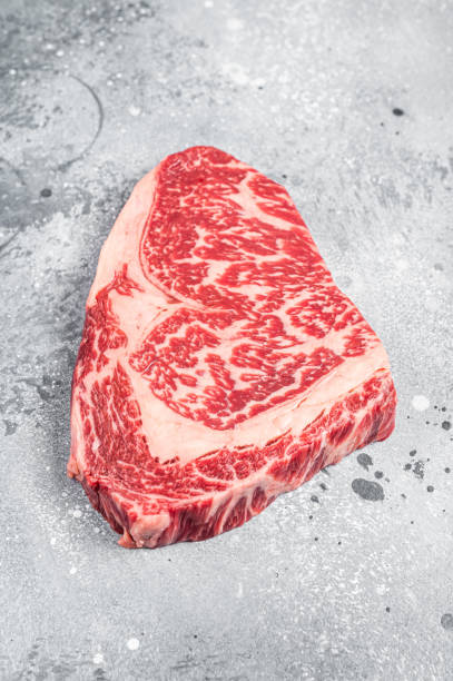 和牛リブアイビーフミートステーキ。グレイの背景。平面図 - rib eye steak beef cutting board meat ストックフォトと画像