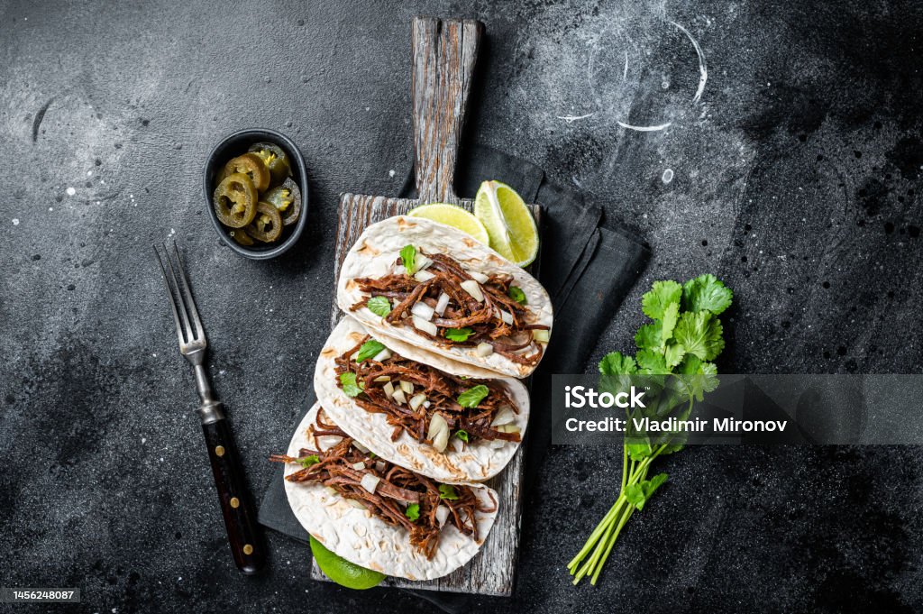 Pork carnitas tacos on corn tortillas with onion and lime. Black background. Top view Pork carnitas tacos on corn tortillas with onion and lime. Black background. Top view. Avocado Stock Photo