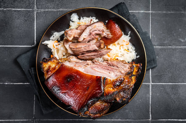 istock Roast Pork Ham Hock, knuckle with Sauerkraut on a plate. Black background. Top view 1456249427