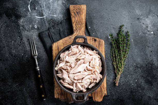 istock Sliced Pieces of chicken meat in a skillet, pulled chicken. Black background. Top view 1456250960