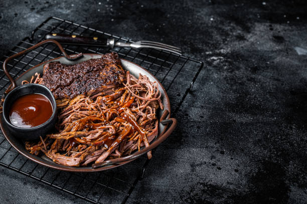 istock Slow Cooked Pulled Beef, Traditional meat rubbed with spices and smoked in a Texas smoker. Black background. Top view. Copy space 1456251104