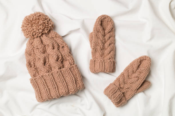 istock Brown winter hat and mittens on white bed sheet. Top view 1456252765