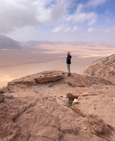 woman standing on a rock, having a great view over wadi rum desert, jordan