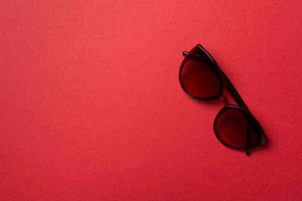 Sunglasses on color background, top view.