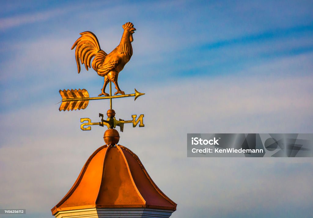 Morning Light on Rooster Weathervane Warm morning light illuminates a copper rooster weathervane atop a cupula in Lancaster County, Pennsylvania. Weather Vane Stock Photo