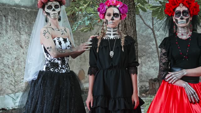 Slow motion Costume performance group portrait of three Women in the guise of Holy Death. Traditional Dia de Los Muertos Festival in Mexico