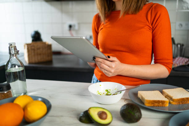 istock Mid adult woman using digital tablet while preparing healthy breakfast 1456256380