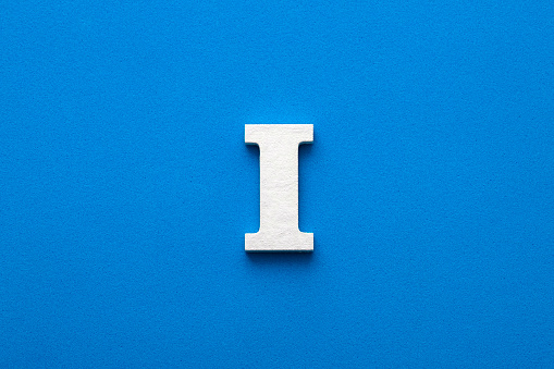 Letra del alfabeto I - Letra blanca de madera sobre fondo azul espumoso photo