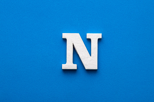 Alphabet letter N - White wooden letter on blue foamy background