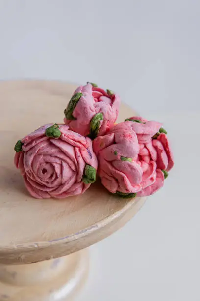 On a wooden round background lie natural marshmallows in the form of pinkroses flowers. Sweet desserts without sugar. Creative baking confectioners. Copy space, mock up. Sweet food