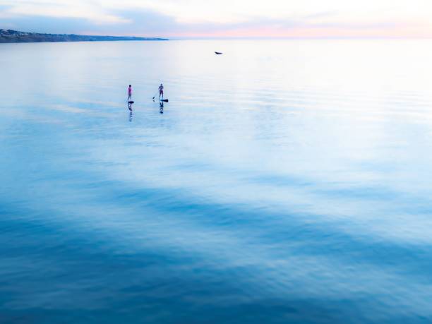 istock One person in silhouette paddle boarding at sunset 1456264237