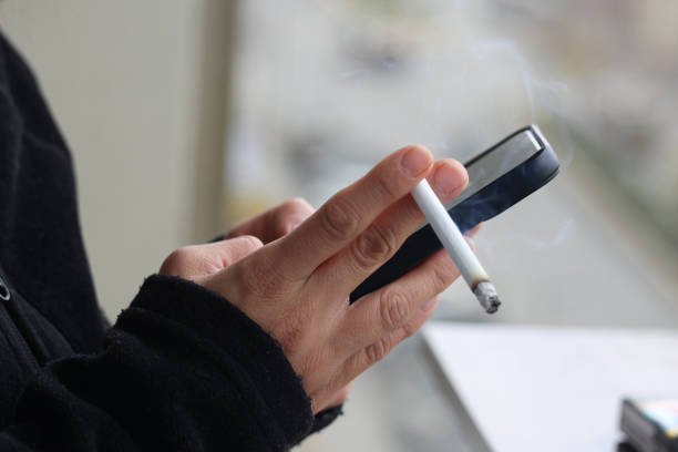 istock Woman holding smartphone and cigarette 1456272288