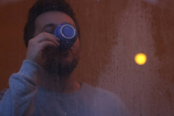 istock A young man drinking coffee behind dirty glass 1456273044