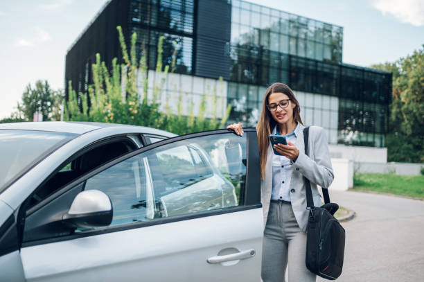istock Business woman getting into the car and using smartphone 1456274824