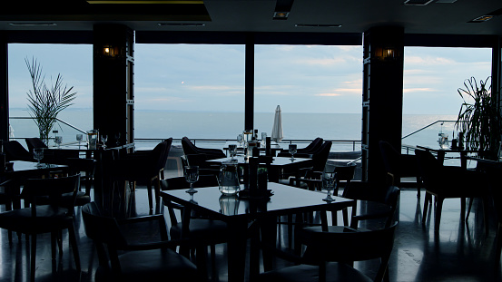 Stunning panoramic sea view in modern restaurant. Stylish interior design in luxury lounge bar background. Summer evening in cozy hotel cafe. Luxury dinner concept.