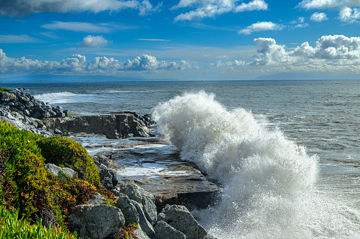 Turbulent ocean waves crashing along the California coast, under a cloudy sky, where a storm had just passed  through.\n\nTaken at Santa Cruz, California, USA