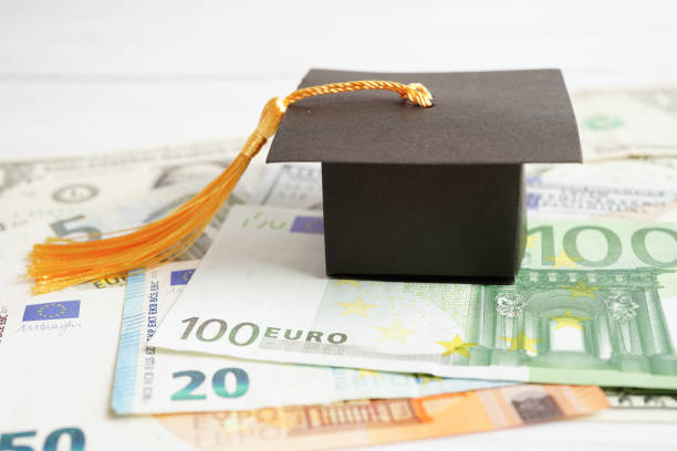 istock Graduation gap hat on Euro and US dollar banknotes money, Education study fee learning teach concept. 1456285879