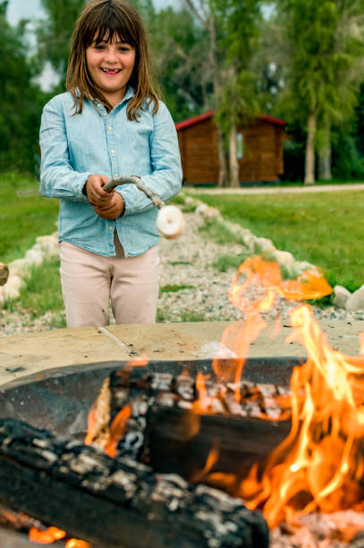 istock Cute kid roasts marshmallows making s’mores over a campifire 1456290114