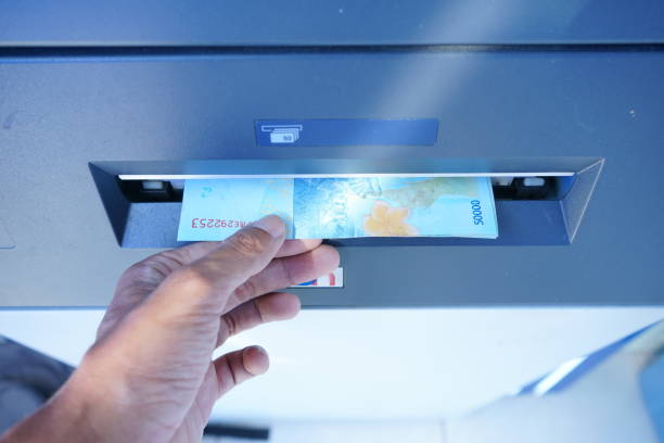 Asian man's hand is taking rupiah notes coming out of the ATM machine this photo was taken on january 13, 2023 in yogyakarta city indonesia.