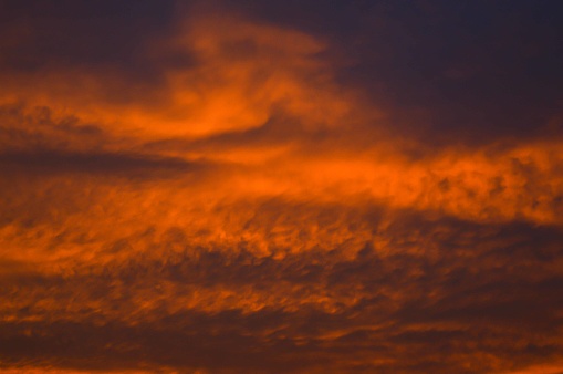 Setting sun creates fiery color in clouds.  Horizontal.