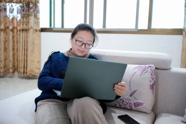 istock A woman sits on a couch using a laptop 1456304724
